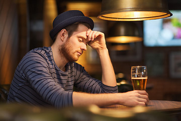 Image showing unhappy lonely man drinking beer at bar or pub