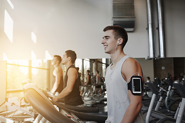 Image showing man with smartphone exercising on treadmill in gym