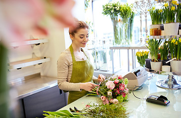 Image showing smiling florist woman making bunch at flower shop