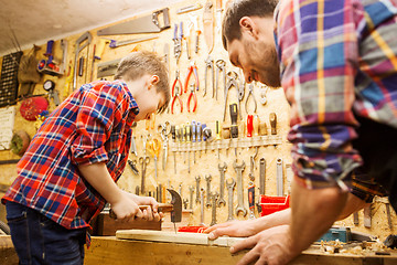 Image showing father and son with hammer working at workshop