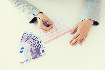 Image showing close up of hands with lottery ticket and money