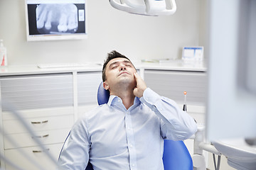 Image showing man having toothache and sitting on dental chair