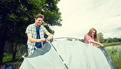 Image showing happy couple setting up tent outdoors