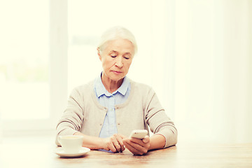 Image showing senior woman with smartphone texting at home