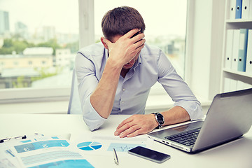 Image showing stressed businessman with papers in office