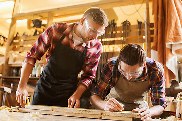 Image showing carpenters with ruler and wood plank at workshop