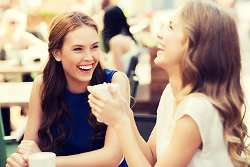 Image showing smiling young women with coffee cups at cafe