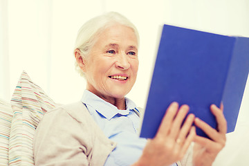 Image showing happy smiling senior woman reading book at home