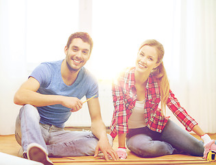 Image showing smiling couple measuring wood flooring