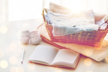 Image showing close up of baby clothes for newborn and notebook
