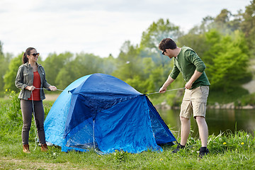 Image showing happy couple setting up tent outdoors