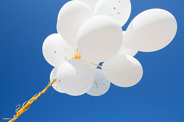 Image showing close up of white helium balloons in blue sky