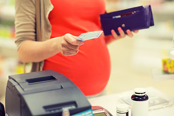 Image showing pregnant woman with money at cashbox in drugstore