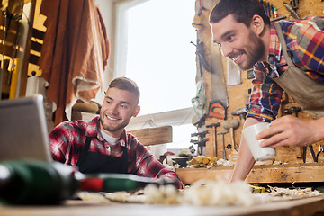 Image showing two smiling carpenters with laptop at workshop