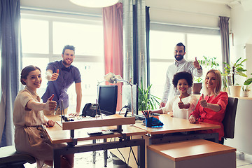 Image showing happy creative team showing thumbs up in office