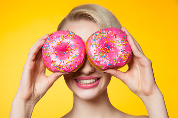 Image showing Short-haired model covering eyes behind two pink donuts