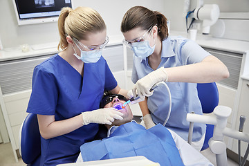 Image showing dentists treating male patient teeth at clinic