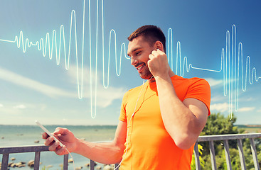 Image showing smiling young man with smartphone and earphones