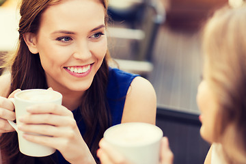Image showing smiling young women with coffee cups at cafe