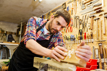 Image showing carpenter working with plane and wood at workshop