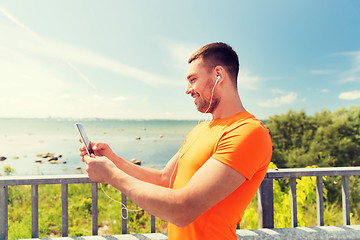 Image showing smiling young man with smartphone and earphones