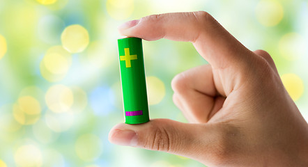 Image showing close up of hand holding green alkaline battery