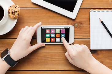 Image showing close up of woman with smartphone on wooden table