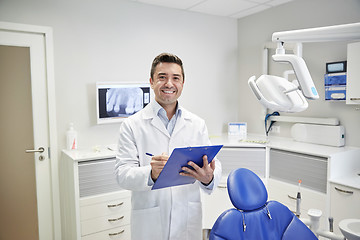 Image showing happy male dentist with clipboard at dental clinic