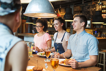 Image showing happy friends eating and drinking at bar or pub