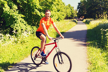 Image showing happy young man riding bicycle outdoors