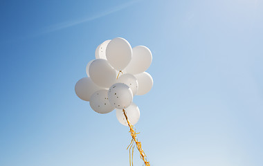 Image showing close up of white helium balloons in blue sky