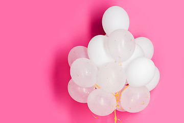 Image showing close up of white helium balloons over pink