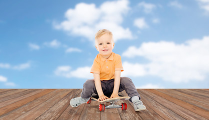 Image showing happy little boy sitting on skateboard