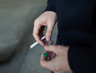 Image showing close up of addict hands with marijuana joint tube