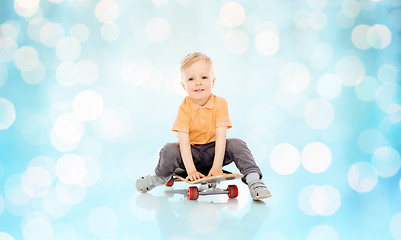 Image showing happy little boy sitting on skateboard