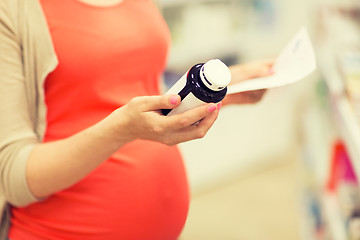 Image showing pregnant woman with medication jar at pharmacy