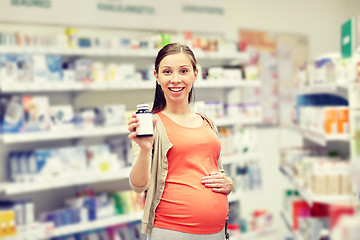 Image showing happy pregnant woman with medication at pharmacy