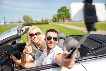 Image showing happy couple in car taking selfie with smartphone