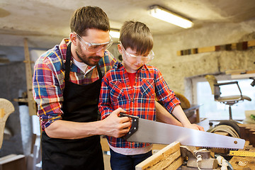 Image showing father and son with saw working at workshop