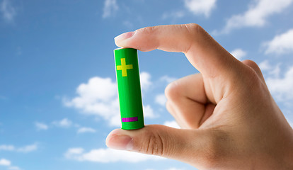 Image showing close up of hand holding green alkaline battery