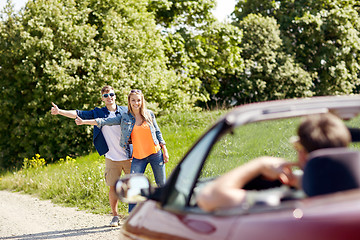 Image showing couple hitchhiking and stopping car on countryside