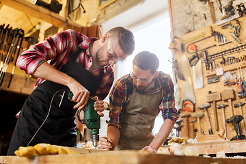 Image showing carpenters with drill drilling plank at workshop