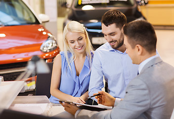 Image showing happy couple with car dealer in auto show or salon