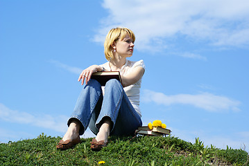 Image showing female student outdoor on gren grass with books and blue sky on