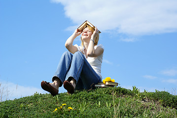 Image showing female student outdoor on gren grass with books and blue sky on