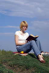 Image showing female student outdoor on gren grass with books and blue sky on