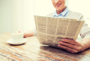 Image showing senior woman with coffee reading newspaper at home