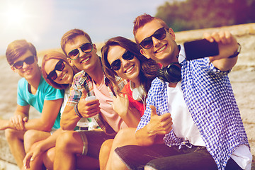 Image showing group of smiling friends with smartphone outdoors