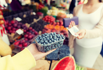 Image showing pregnant woman with money buying berries at market