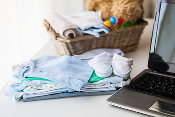 Image showing close up of baby clothes, toys and laptop